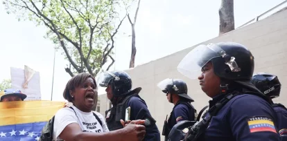 Una persona (2-i) reacciona ante un integrante del Cuerpo de Policía Nacional Bolivariana (CPNB)
