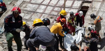Fotografía de rescatistas recuperando un cuerpo de los escombros de un edificio afectado por los terremotos, este miércoles, en La Guaira (Venezuela).