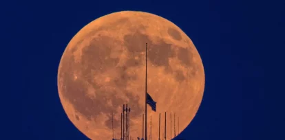 La Luna llena se alza por detrás del ayuntamiento en el centro de Kansas City, Misuri, antes de un eclipse lunar, el 27 de agosto de 2026. (AP Foto/Charlie Riedel)