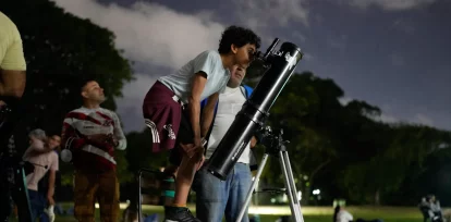 Un niño mira a la Luna a través de un telescopio durante un eclipse lunar parcial, en Caracas, Venezuela, el 27 de agosto de 2026. (AP Foto/Ariana Cubillos)