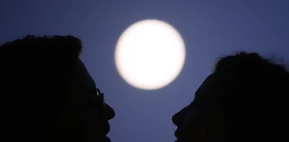 Una pareja se abraza frente a la Luna llena, horas antes de un eclipse lunar parcial, en el mirador de Santa Lucía, en Lisboa, el 27 de agosto de 2026. (AP Foto/Armando Franca)