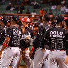 Erik González, centro, de los Leones del Escogido, celebra con sus compañeros tras anotar en carrera.
