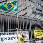 Un obrero ata una bandera a la verja de la sede de Petrobras durante una protesta de empleados. 
