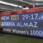 La etíope Almaz Ayana posa junto al marcador que muestra su nuevo récord mundial en la final de los 10.000 metros para mujeres, en el primer día de actividades del atletismo en los Juegos Olímpicos de Río de Janeiro, Brasil, el viernes 12 de agosto de 2016. (AP Foto/Matt Slocum)