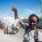 Una mujer vende mascarillas cerca de la entrada del Parque industrial, en el primer día en que su uso es obligatorio, este lunes en Puerto Príncipe. EFE