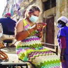 Una mujer que usa una máscara para frenar la propagación del nuevo coronavirus mira su teléfono móvil mientras viaja en un carrito de bicicleta en La Habana, Cuba, el miércoles 23 de diciembre de 2020.  Cuba producirá 100 millones de dosis de su vacuna contra el nuevo coronavirus Soberana 02 (AP Foto/Ramón Espinosa)