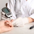Doctor checking blood sugar level with glucometer at table. Diabetes test
