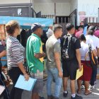 MEX2408. TAPACHULA (MÉXICO), 07/02/2025.- Migrantes hacen fila frente a las instalaciones de la Comisión Mexicana de Ayuda a Refugiados (Comar) este viernes, en Tapachula (México). Organizaciones mexicanas que atienden a migrantes, mujeres y personas LGTBI alertan del riesgo de desaparecer ante la parálisis de la Agencia de Estados Unidos para el Desarrollo Internacional (Usaid), pero la presidenta de México, Claudia Sheinbaum, cree que es mejor que cierre". EFE/ Juan Manuel Blanco