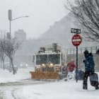 Peatones transitan por una acera  mientras un camión  limpia la carretera en el barrio de Brooklyn, Nueva York.