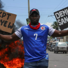 Un hombre sostiene carteles con la leyenda "¡Apártense! ¡Abajo el Consejo Presidencial!" y "Renuncia incondicional" durante una protesta contra el consejo presidencial de transición de Haití, en Puerto Príncipe, el 15 de mayo de 2025. © Reuters - Jean Feguens Regala