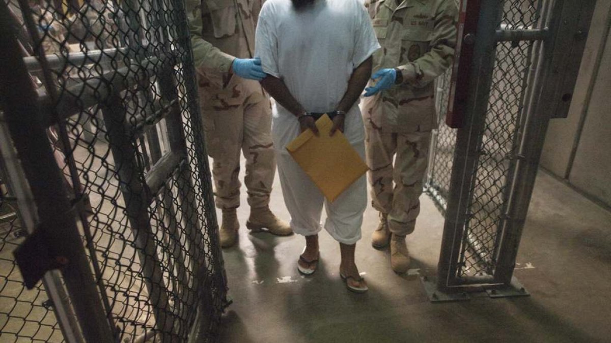 (FILES) This March 30, 2010 file photo shows US military guards as they move a detainee inside Camp VI at Guantanamo Bay, Cuba. Six Guantanamo detainees have been transferred to Uruguay from the American military base in Cuba, where 136 detainees remain, the Pentagon said December 7, 2014. Among the inmates transferred was Syrian prisoner Jihad Diyab, 43, who had staged a hunger strike and requested a US court to order prison officials to stop force-feeding him. The six men — including three other Syrians, a Palestinian and a Tunisian — received an «approved for transfer» from US authorities and left the military base on a US Air Force plane at 12:00 am (0500 GMT) Sunday, Pentagon spokesman Myles Caggins told AFP. There are still 136 prisoners at Guantanamo, most of whom are detained without charge or facing trial. Sixty-seven of them have been approved for release by the successive governments of George W. Bush and Barack Obama. AFP PHOTO/Paul J. Richards / FILES