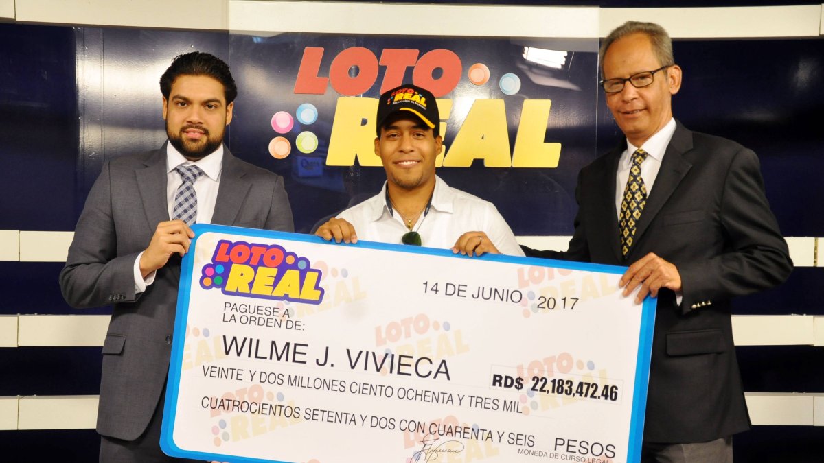 Ejecutivos de Loto Real entregan un cheque por RD$22 millones a Wilme de Jesús Vivieca Guzmán.