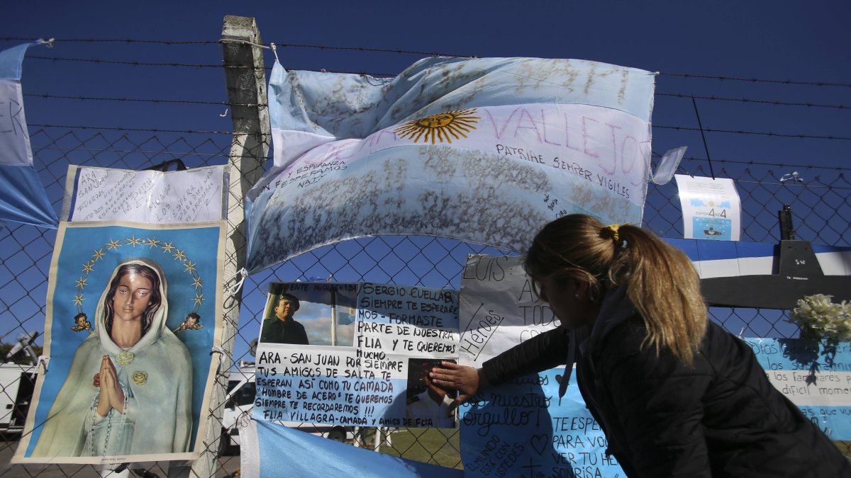 Un familiar de uno de los miembros del submarino desaparecido en Argentina coloca su mano sobre una fotografía en la base naval en Mar de Plata, Argentina.