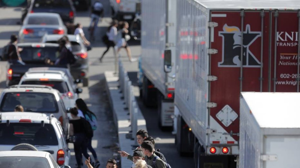 People wave for rides as cars and trucks line up to enter Mexico from the U.S., at a border crossing in El Paso, Texas, Friday, March 29, 2019. Threatening drastic action against Mexico, President Donald Trump declared on Friday that he is likely to shut down America's southern border next week unless Mexican authorities immediately halt all illegal immigration. Such a severe move could hit the economies of both countries, but the president emphasized,