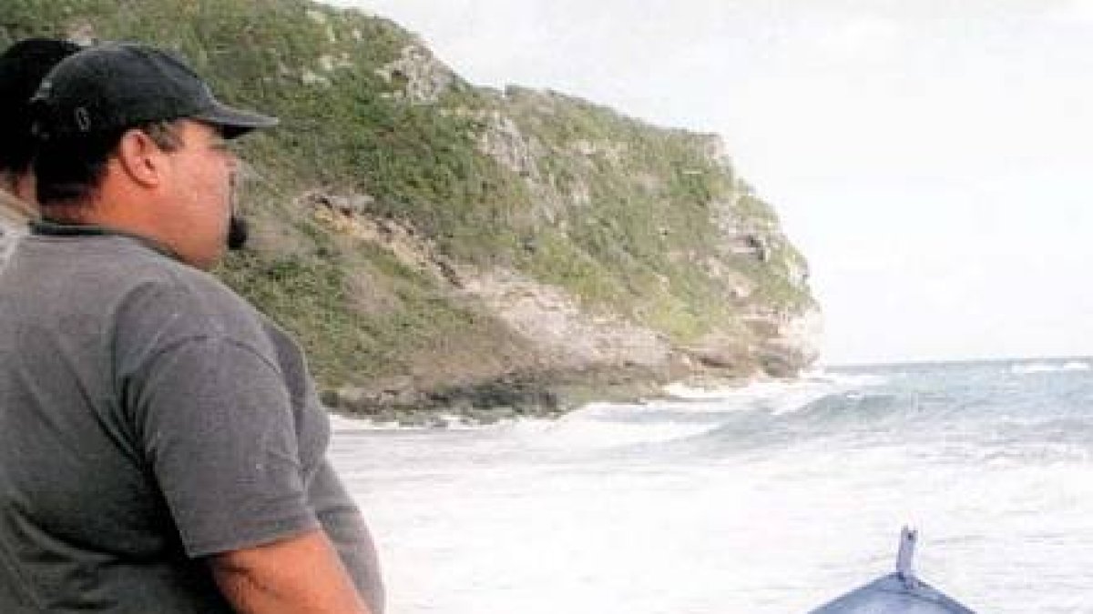 Residents look at at a boat that washed up on El Pastillo beach which was carrying illegal Dominican migrants and landed off the coast of Isabela, Puerto Rico, Wednesday, March 8, 2000. An unknown number of migrants from this boat made it safely to shore. Another boat carrying an estimated 63 migrants broke apart in heavy surf in the same area, killing at least seven people and leaving dozens missing. (AP Photo/Javier Gonzalez) PUERTO RICO OUT