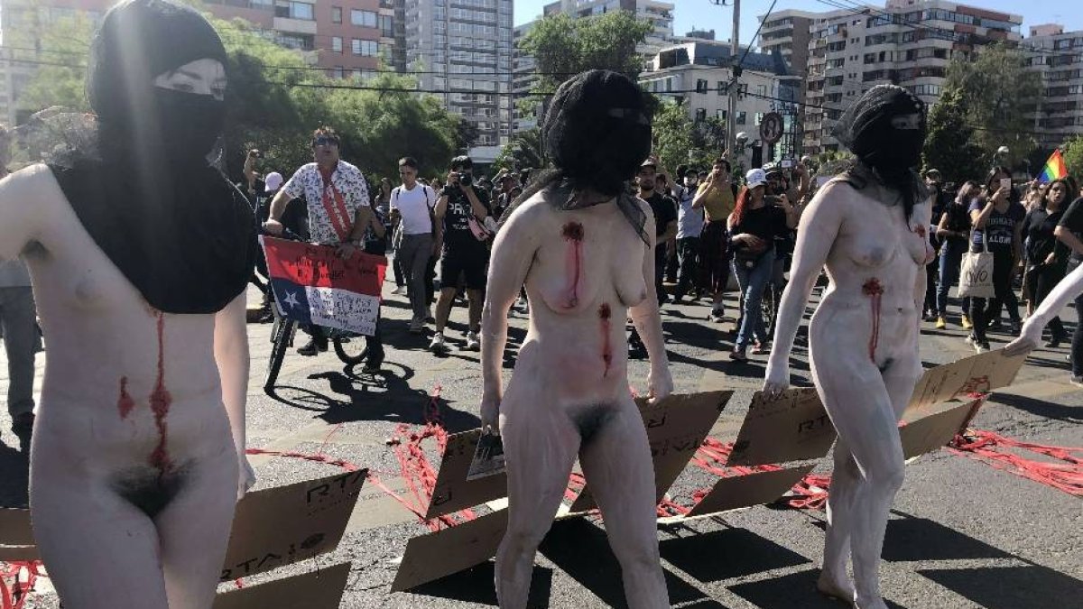 CH01. SANTIAGO (CHILE), 28/10/2019.- Manifestantes desnudos con los cuerpos pintados de blanco portan este lunes carteles con los nombres de los 20 fallecidos en las protestas de Chile, este lunes frente a una comisaría de Carabineros, en Santiago (Chile), mientras se desarrolla una audiencia en la Fiscalía Sur de Santiago de Chile con un joven universitario homosexual que denuncia haber sido apalizado, torturado, violados y amenazado de muerte por los Carabineros. EFE/Fernando Gimeno