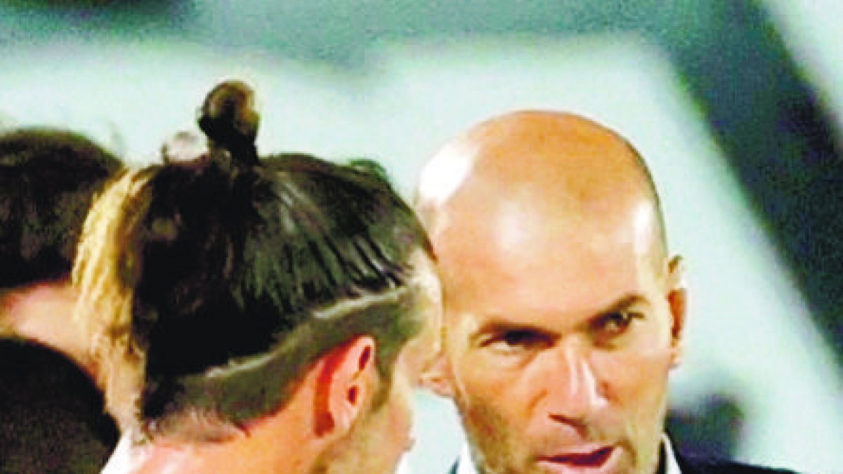 GRAF6622. MADRID, 24/06/2020.- El técnico francés del Real Madrid, Zinedine Zidane, conversa con el jugador galés del equipo blanco, Gareth Bale, durante el tiempo de hidratación en el encuentro correspondiente a la jornada 31 de primera división que disputan esta noche frente al Real Mallorca en el estadio Alfredo Di Stéfano, en Madrid. EFE/JuanJo Martín
