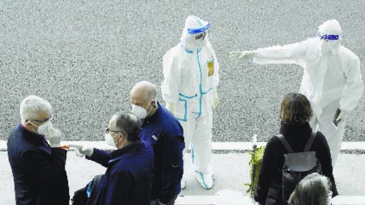 FILE - In this Jan. 14, 2021, file photo, a worker in protective gear directs members of the World Health Organization (WHO) team on their arrival at the airport in Wuhan in central China's Hubei province. A relative of a coronavirus victim in China is demanding to meet the visiting World Health Organization expert team, saying it should speak with affected families who allege they are being muffled by the Chinese government. (AP Photo/Ng Han Guan, File)