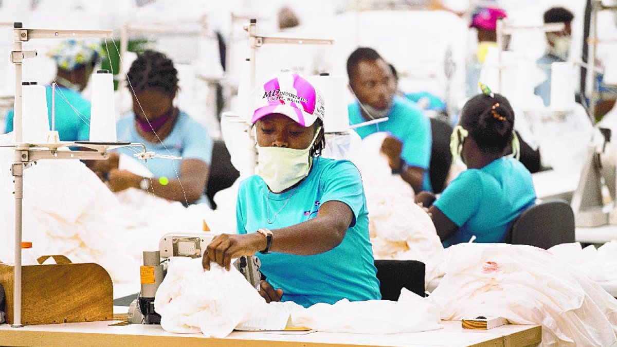 ACOMPAÑA CRÓNICA: R.DOMINICANA HAITÍ AME6420. DAJABÓN (REPÚBLICA DOMINICANA), 10/05/2021.- Empleados trabajan cosiendo ropa en una de las 28 naves del parque industrial Codevi, el 6 de mayo de 2021 en Dajabón (R.Dominicana). En las 28 naves industriales del Codevi la actividad no cesa. Más de 14.000 haitianos uniformados cosen ropa sin parar, en un ambiente de trabajo organizado que contrasta con el alboroto y el caos que reina en las calles de Ouanaminthe. EFE/ Orlando Barría
