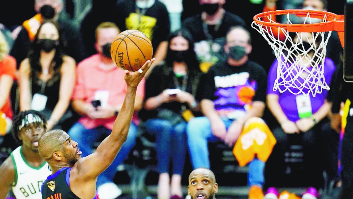 Phoenix Suns guard Chris Paul (3) scores as Milwaukee Bucks forward Khris Middleton (22) and Bucks guard Jrue Holiday, left, look on during the second half of Game 1 of basketball's NBA Finals, Tuesday, July 6, 2021, in Phoenix. (AP Photo/Ross D. Franklin)