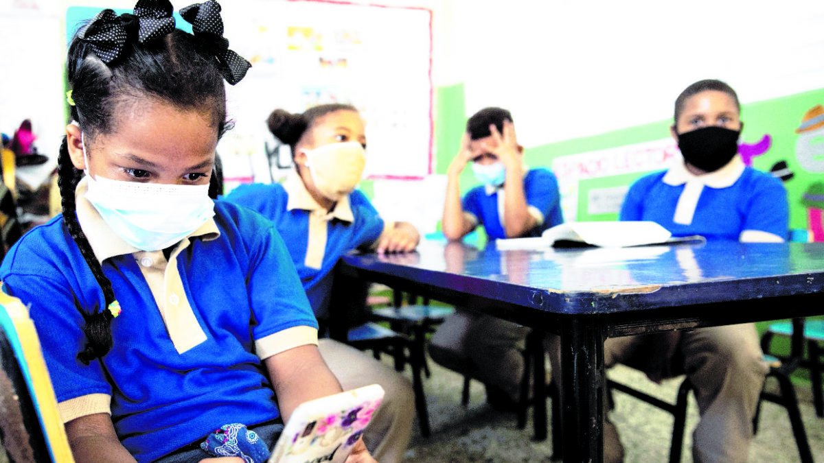 STO01. SANTO DOMINGO (REPÚBLICA DOMINICANA), 02/11/2020.- Estudiantes, hijas de profesoras, acompañan a sus madres a la escuela Eulalio Arias, durante el acto de inicio oficial del año escolar, este lunes en Santo Domingo. República Dominicana inicia el año escolar de manera 100% virtual, para más de dos millones de estudiantes, con clases por radio y televisión, debido a la pandemia de la covid-19. EFE/ Orlando Barría
