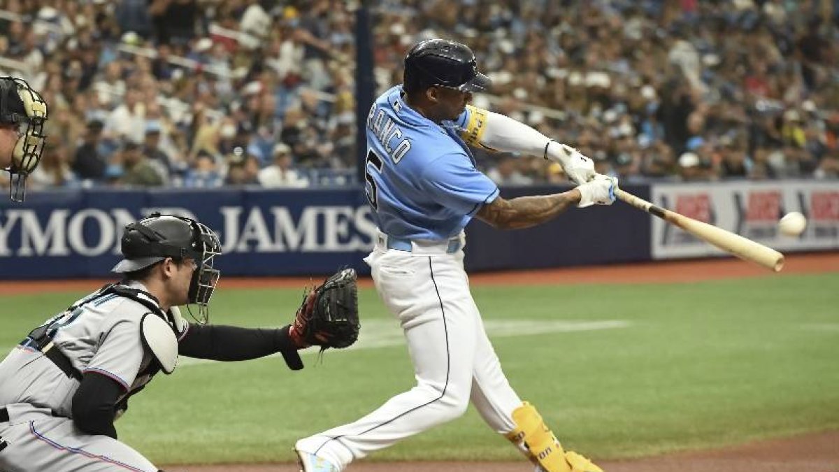 Home plate umpire Jeff Nelson (45) and Miami Marlins catcher Alex Jackson, center, look on as Tampa Bay Rays' Wander Franco (5) hits a double during the first inning of a baseball game Sunday, Sept. 26, 2021, in St. Petersburg, Fla. Franco extended his on-base consecutive game streak to 41. (AP Photo/Steve Nesius)