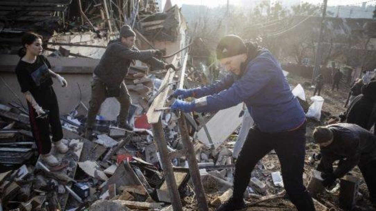 Kyiv (Ukraine), 03/01/2023.- Volunteers clean debris at the site of a Russian missile attack that occured on 31 December 2022 in Kyiv, Ukraine, 03 January 2023. Russian missiles targeted major cities across Ukraine on 31 December prior to the New Year celebration. Russian troops entered Ukraine on 24 February 2022 starting a conflict that has provoked destruction and a humanitarian crisis. (Atentado, Rusia, Ucrania) EFE/EPA/MIKHAIL PALINCHAK