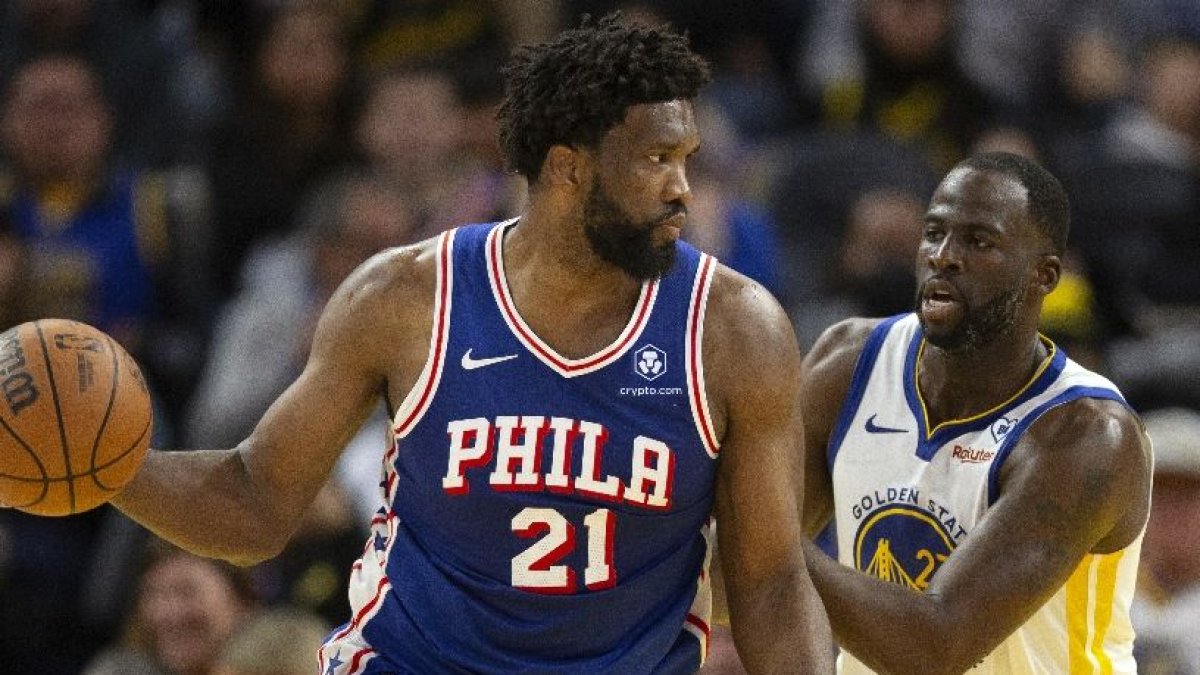 Joel Embiid, iz, defiende el balón ante Draymond Green.