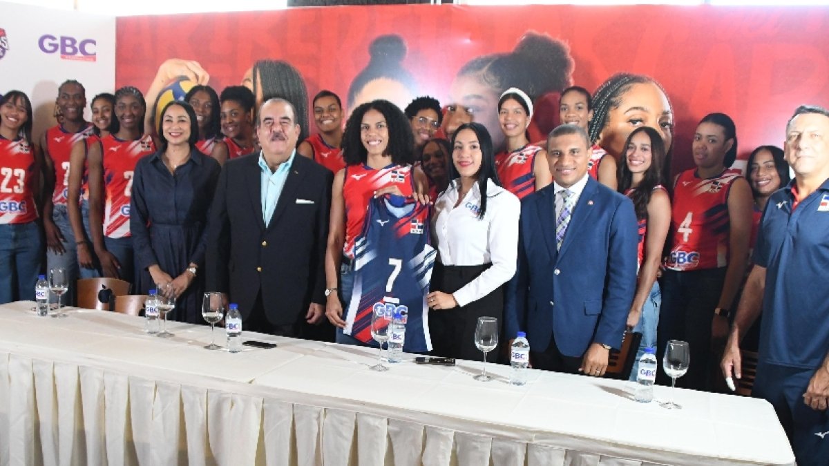 Momentos en que la gerente de Mercadeo del Grupo GBC, Francisca Santana, hace entrega de la camiseta a Niverka Marte. Figuran Marte Hoffiz, Milagros y las jugadoras.