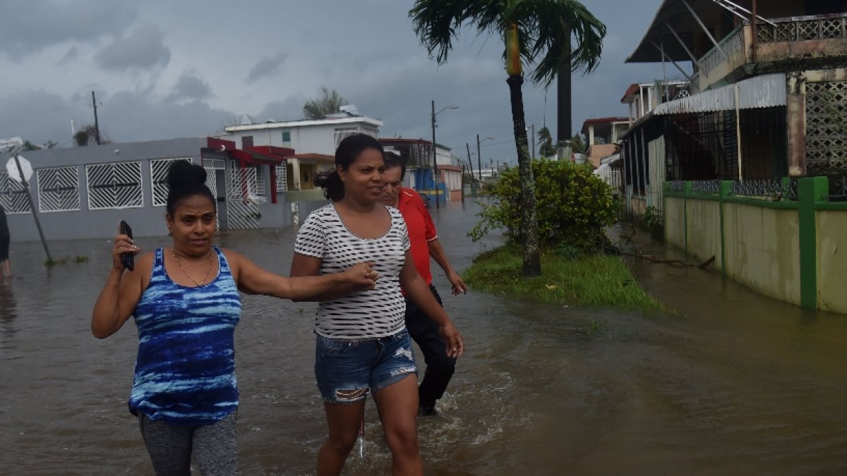 Inhabitants walk in flood water from the Puerto Nuevo river during the passage of Hurricane Maria, in the neightborhood Puerto Nuevo, in San Juan, Puerto Rico, on September 20, 2017. Maria slammed into Puerto Rico on Wednesday, cutting power on most of the US territory as terrified residents hunkered down in the face of the island's worst storm in living memory. After leaving a deadly trail of destruction on a string of smaller Caribbean islands, Maria made landfall on Puerto Rico's southeast coast around daybreak, packing winds of around 150mph (240kph).
 / AFP / HECTOR RETAMAL