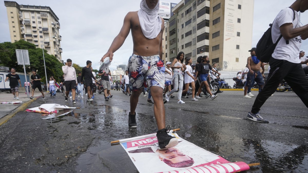 A protester steps on a campaign sign of President Nicolas Maduro during a march against hish being declared the winner of the presidential election, the day after the vote in Caracas, Venezuela, Monday, July 29, 2024. (AP Photo/Fernando Vergara)