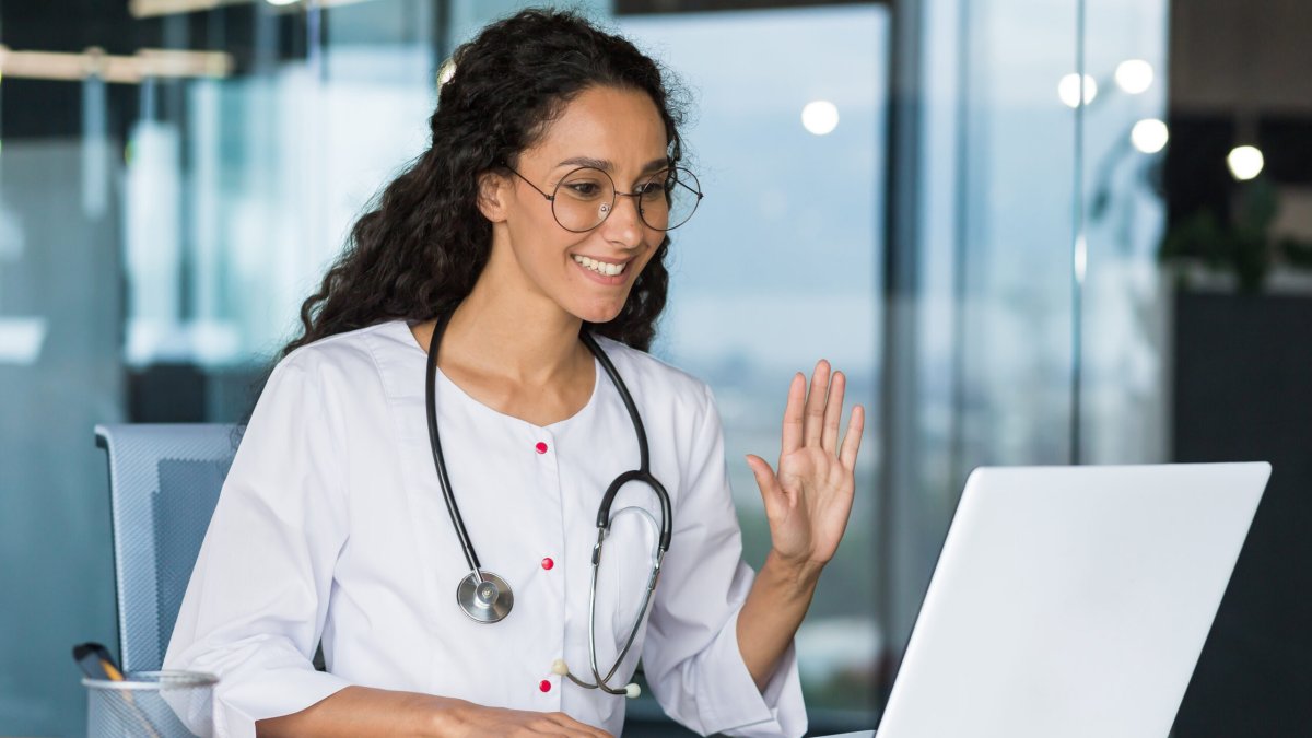 Young Latin American female doctor consults online patients via video connection from a laptop