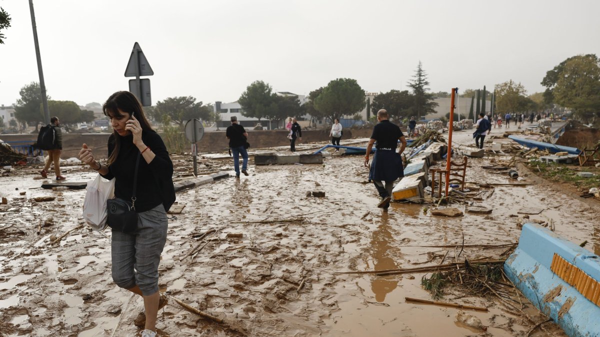 Una mujer camina entre el lodo acumulado por las intensas lluvias de la fuerte dana que afecta especialmente el sur y el este de la península ibérica, este miércoles en Picaña (Valencia). EFE/Biel Aliño