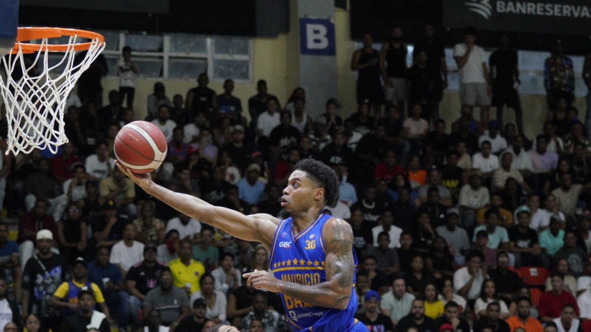 El canastero Jherry Matos, de  Mauricio Báez, con gran atleticidad, busca poner la bola en el aro ante Fausto Pichardo, de Bameso.  (Hoy/Manolito Jiménez)