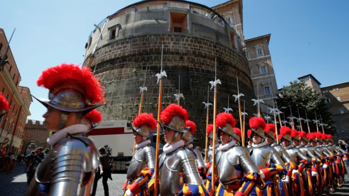 La élite de la Guardia Suiza del Vaticano marcha frente a la torre del banco del Vaticano, en el Vaticano