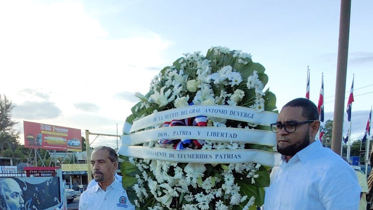 El presidente de Efemérides Patrias y el alcalde de El Seibo, mientras llevan la ofrenda floral para colocarla en la tarja.