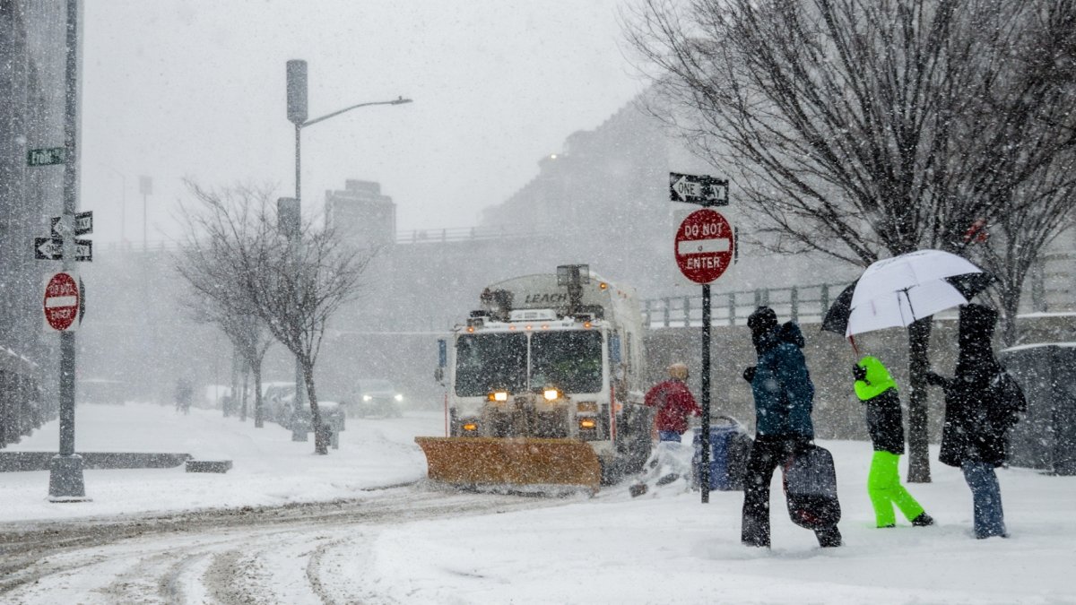 Peatones transitan por una acera  mientras un camión  limpia la carretera en el barrio de Brooklyn, Nueva York.