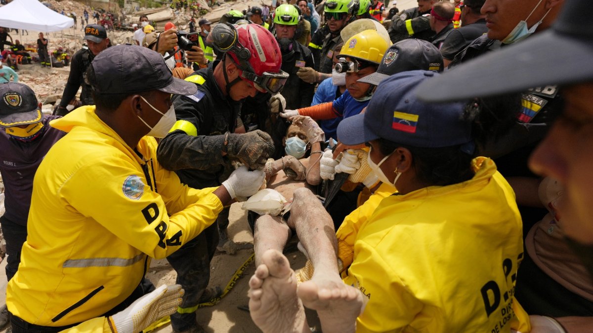 Rescatistas transportan hombre rescatado de entre los escombros de un edificio en La Guaira. EFE