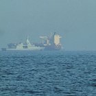 Una patrullera emiratí (izquieda), navega cerca de un petrolero fondeado en el golfo de Omán, cerca del estrecho de Ormuz, vistos desde una carretera costera cerca de Khor Fakkan, Emiratos Árabes Unidos, el 1 de mayo de 2026. (AP Foto/Fatima Shbair)