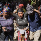 La gente observa cómo los trabajadores del depósito de cadáveres se llevan los cuerpos de sus familiares, asesinados en un ataque de una banda, en el barrio de Kenscoff, en Puerto Príncipe (Haití), el lunes 24 de agosto de 2026. AP Photo/Odelyn Joseph - Odelyn Joseph