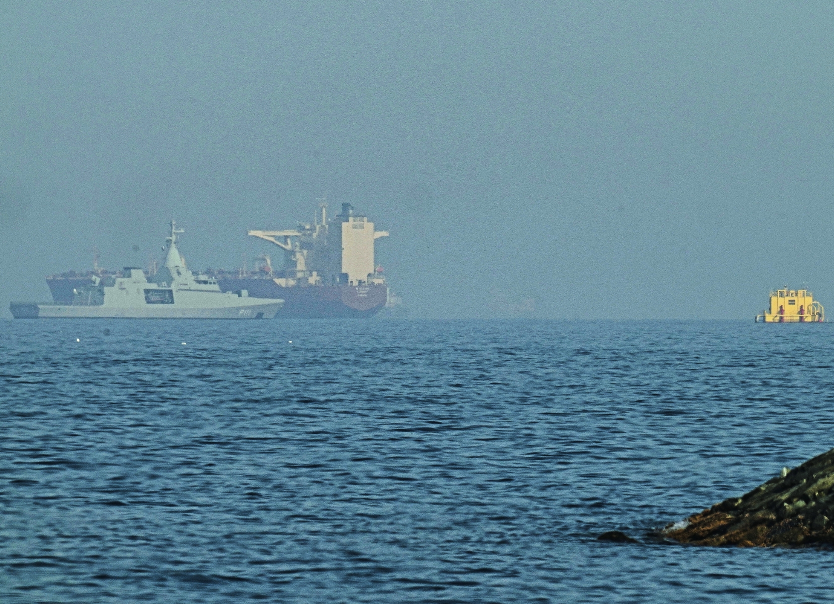 Una patrullera emiratí (izquieda), navega cerca de un petrolero fondeado en el golfo de Omán, cerca del estrecho de Ormuz, vistos desde una carretera costera cerca de Khor Fakkan, Emiratos Árabes Unidos, el 1 de mayo de 2026. (AP Foto/Fatima Shbair)