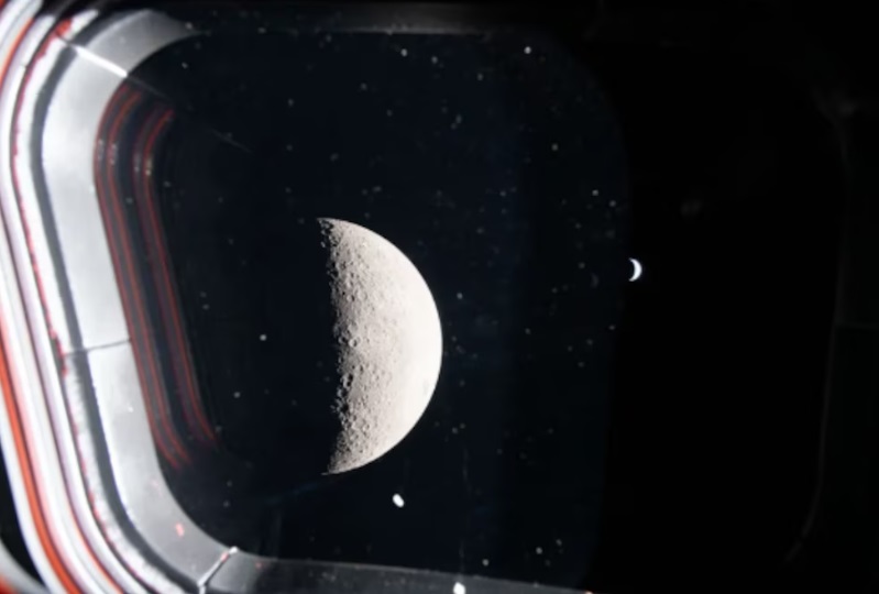 Desde la cara oculta de la Luna, los astronautas tomaron esta fotografía a través de una ventana de la nave espacial Orion. Muestra una luna creciente en primer plano, con una Tierra brillante pero pequeña al fondo. (olla)