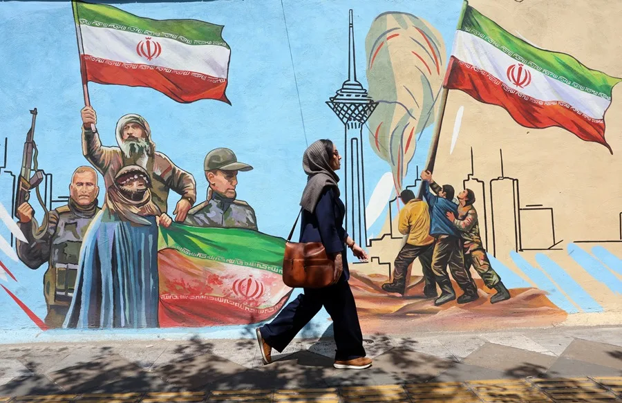 Una mujer camina delante de un mural en Teherán, en una imagen de archivo. EFE/EPA/ABEDIN TAHERKENAREH