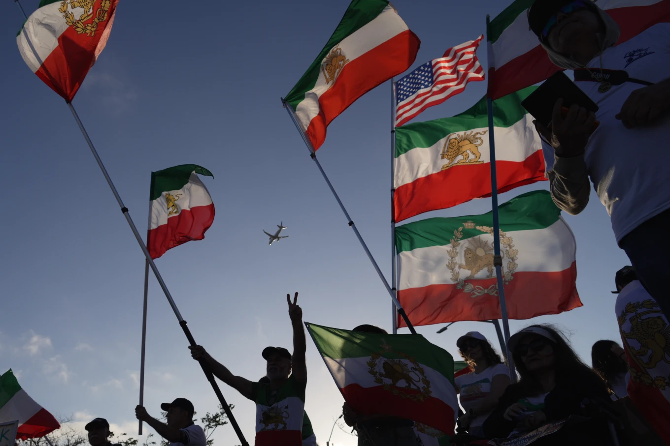 Varias personas ondean banderas iraníes prerrevolucionarias durante una protesta frente a un estadio de Los Ángeles.