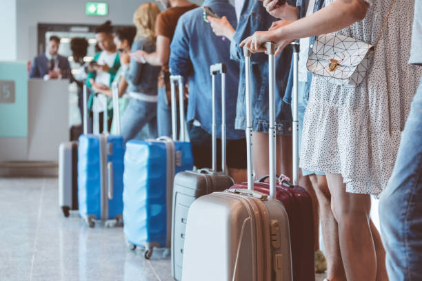 Personas cargan maletas de viaje en un aeropuerto. Foto de referencia