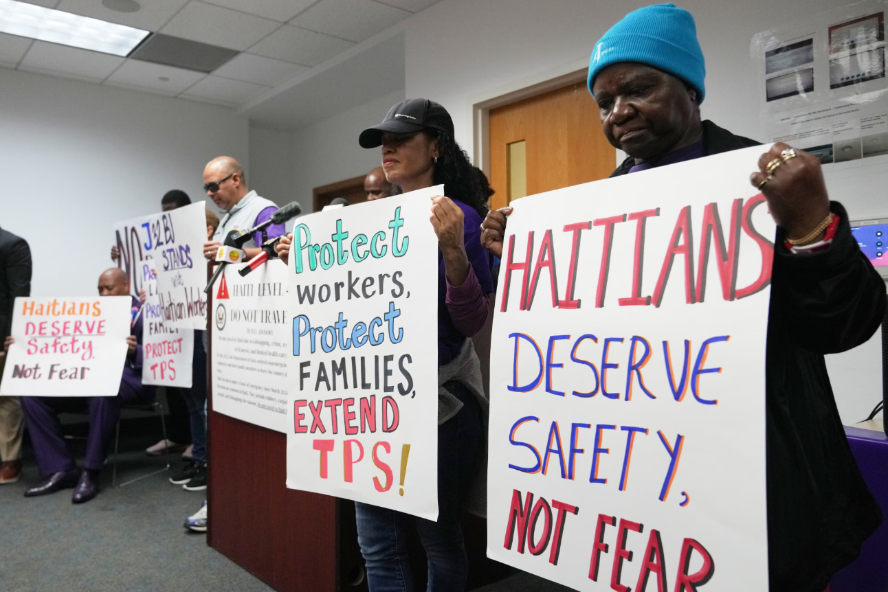 Personas sostienen carteles durante una manifestación en apoyo a la extensión del Estatus de Protección Temporal  para migrantes haitianos