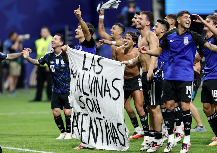 El argentino Lisandro Martínez y Giovanni Lo Celso sostienen una pancarta que dice 