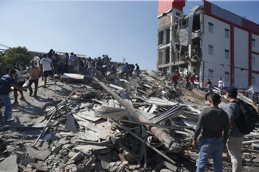 Personas caminan sobre los escombros de un edificio colapsado este lunes, en Cali (Colombia). EFE/ Ernesto Guzmán