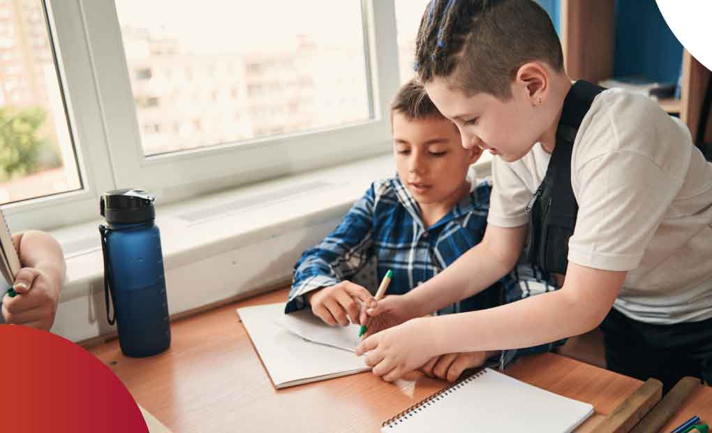Un niño ayuda a otro a hacer su tarea