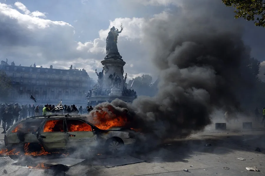 Un automóvil arde en la plaza de la República mientras estallan enfrentamientos entre manifestantes y la policía durante una protesta contra el aumento del coste de la vida y los recortes en París, Francia. EFE/YOAN VALAT